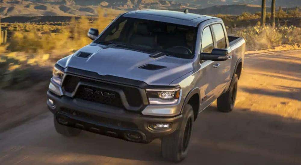 A grey 2021 Ram 1500 is driving on a desert road.