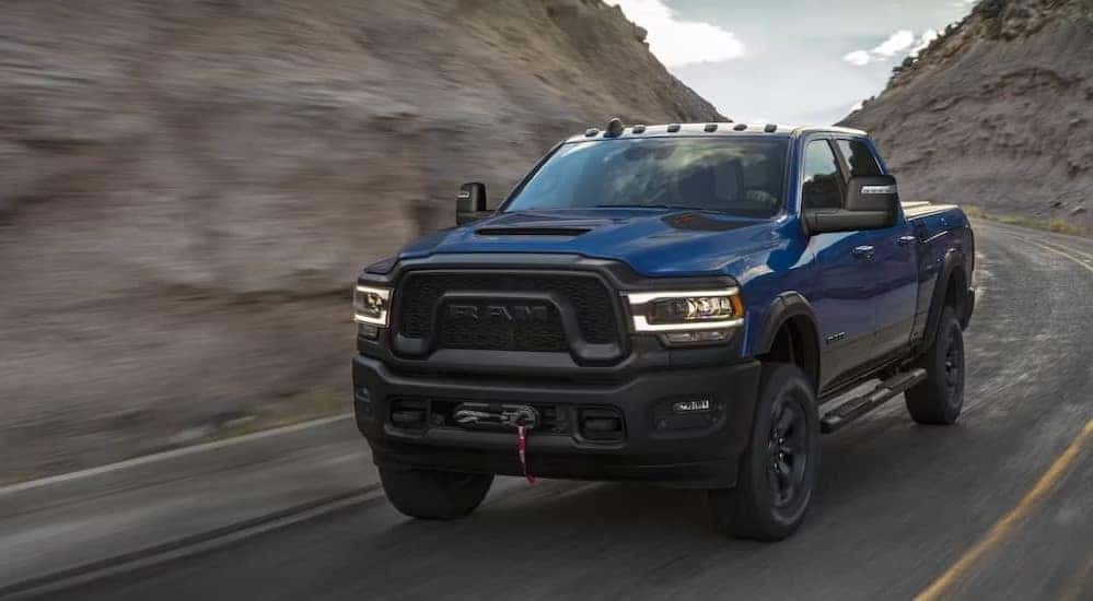 A blue 2024 Ram 2500 for sale near Covington is shown driving on a highway.