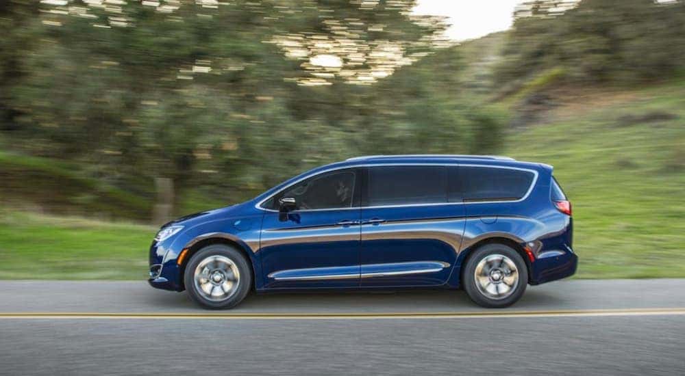 A blue 2019 Chrysler Pacifica, popular among used Chryslers in Lexington, is driving past trees.