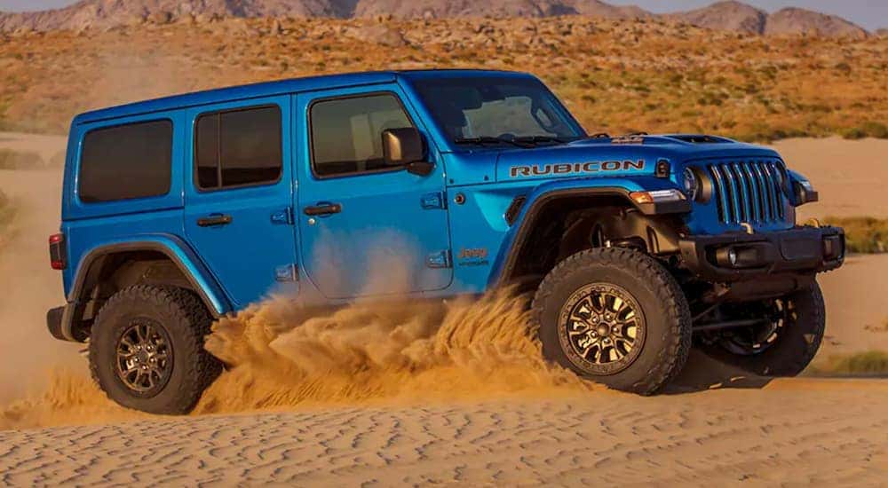 A blue 2021 Jeep Wrangler Rubicon 392 from a Lexington Jeep dealer is off-roading in the sand.