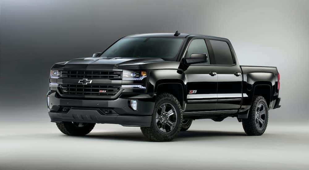 A popular Georgetown used car, a black 2016 Chevy Silverado Z71 Midnight Edition, is shown from the side against a gradient background.
