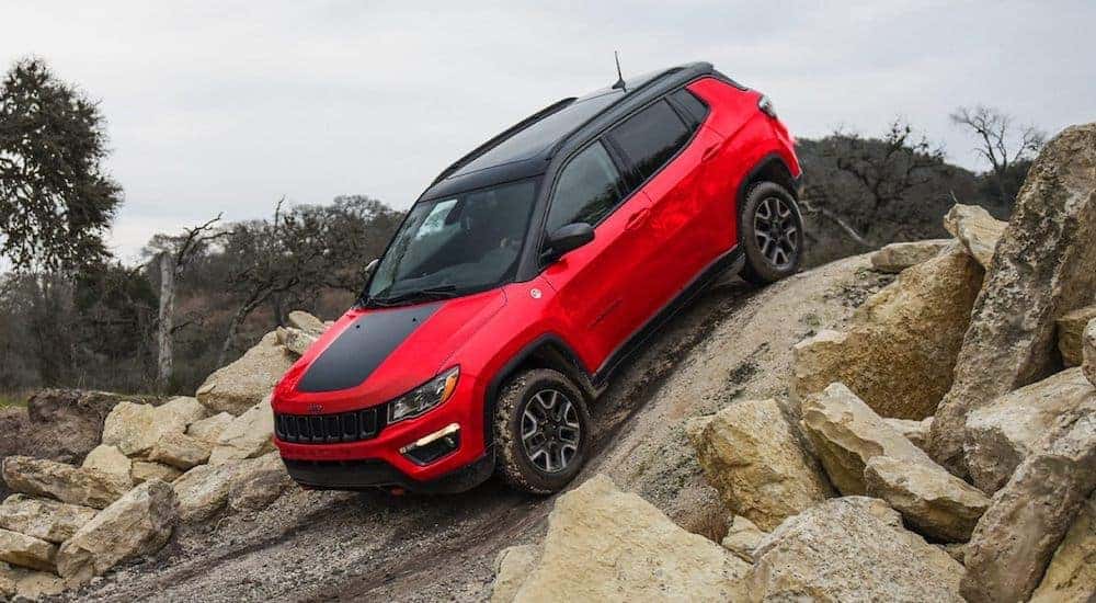 A red and black 2021 Jeep Compass is crawling down a rocky hill.