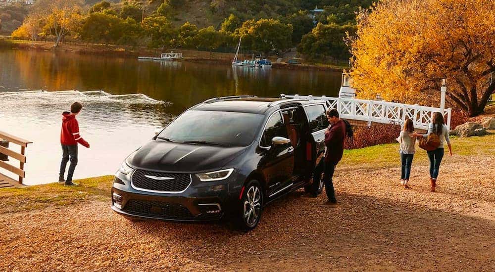 A black 2021 Chrysler Pacifica Pinnacle is shown parked by a lake and a white bridge.