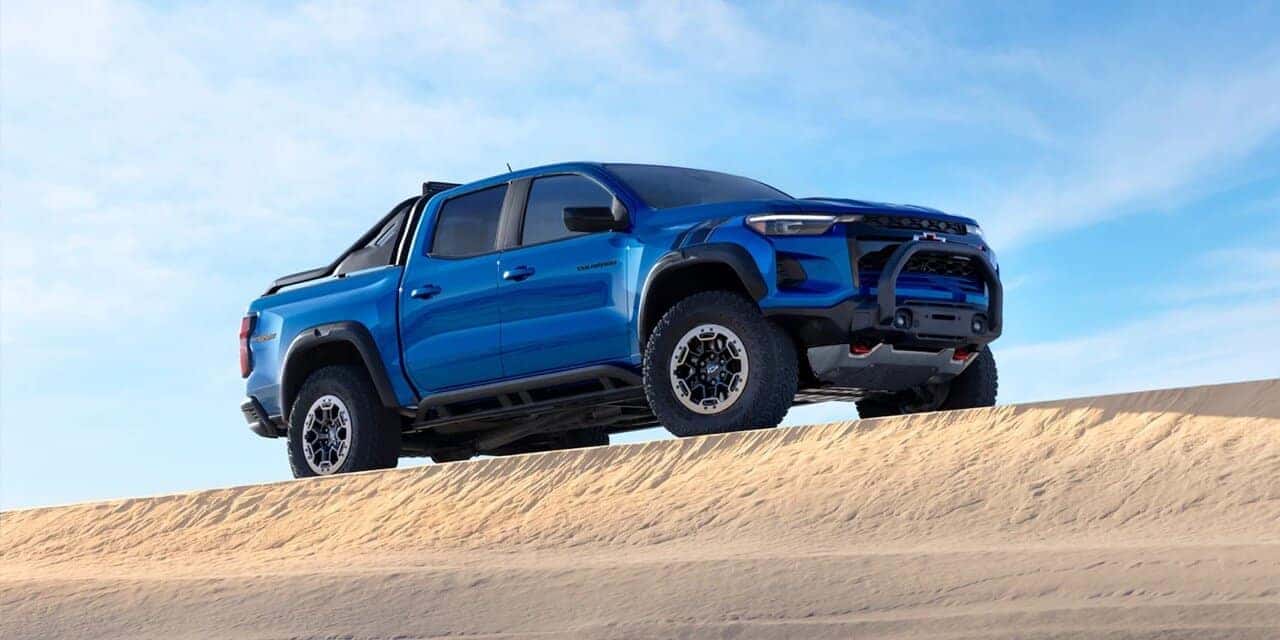 Blue 2023 Chevy colorado parked on top of sand dune