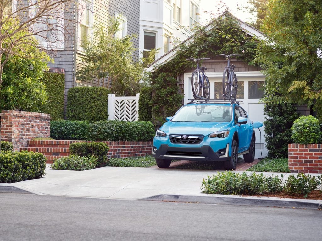 teal Subaru backed into a driveway with bikes mounted on the roof
