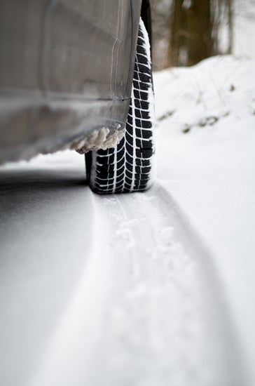 close up of a tire driving through snow