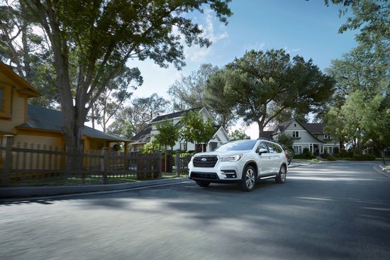 white Subaru Ascent driving through a small neighborhood on a summer day
