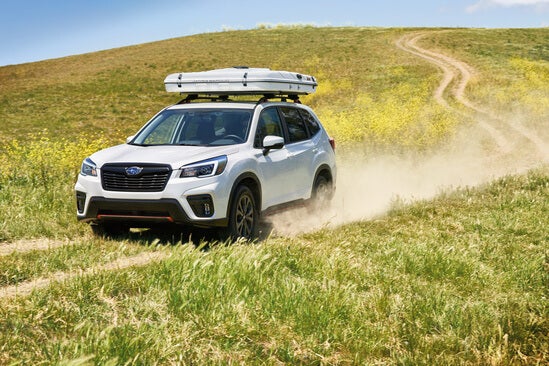 A white Subaru Forester driving through a field