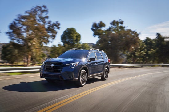 dark blue Subaru driving outside of town on a sunny day