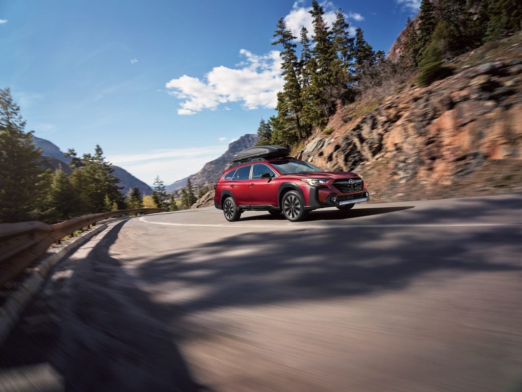red Subaru driving through a windy mountain road
