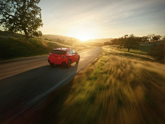 A Subaru Crosstrek driving into the sun