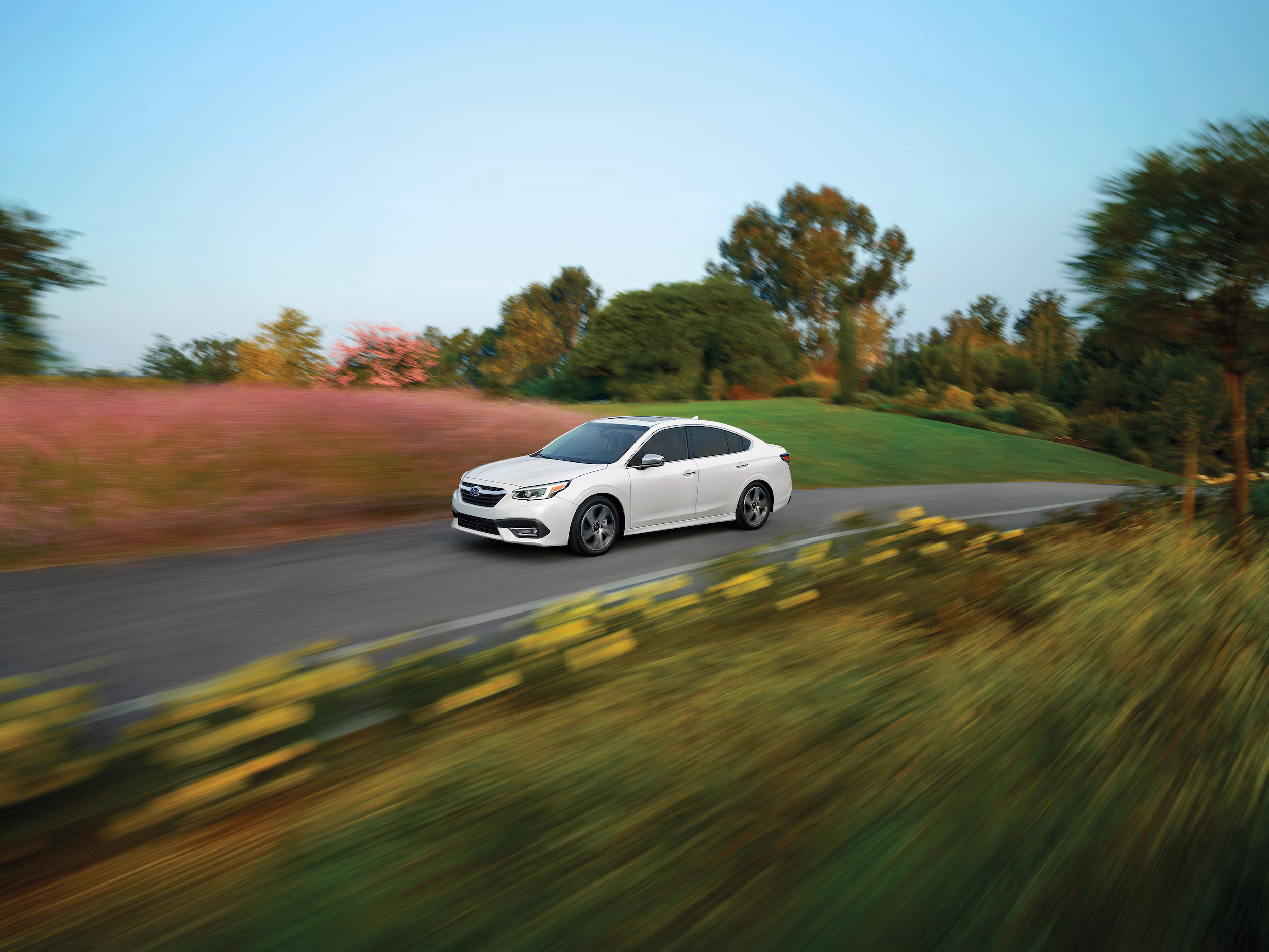 white Subaru driving on a beautiful country road at sunset