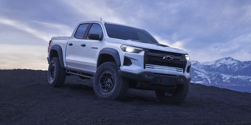 White off-road pickup truck parked on dark rugged terrain at dusk