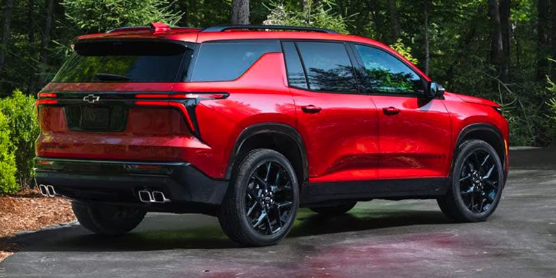 Red SUV parked on a paved driveway in a forested area