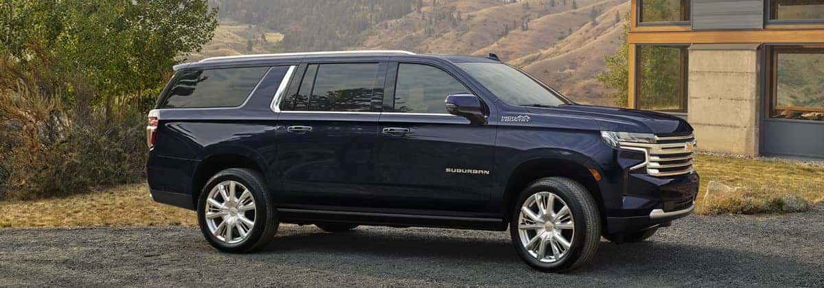 A Chevrolet Suburban SUV driving on a highway through a desert landscape with mountains in the background.
