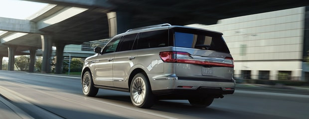 Silver SUV driving on a city street under overpasses, with motion blur conveying speed. The scene is urban and modern, exuding a dynamic feel.