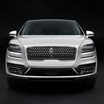 Front view of a sleek, white SUV with a distinctive grille and modern headlights, set against a dark background, conveying a sense of luxury and elegance.