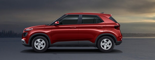 Red SUV parked on a flat surface, under a cloudy sky with a faint sunset. The vehicle is viewed from the side, highlighting its sleek design.