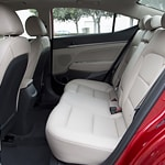The image shows the interior of a car, focusing on the backseat. The seats are upholstered in light beige leather, and there's a sleek, modern design.