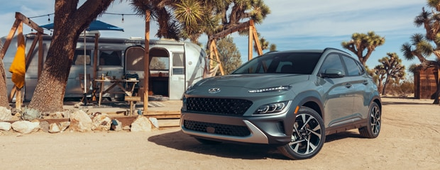 Gray SUV parked in a desert campsite with an Airstream trailer, picnic table, and Joshua trees under a bright blue sky, evoking adventure and freedom.