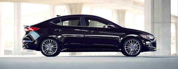 Sleek black sedan parked indoors, showcasing a glossy exterior and modern alloy wheels. The setting is bright, highlighting the car's elegant design.