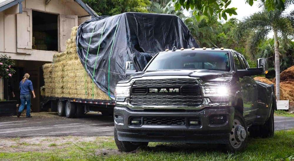 A popular used Ram diesel, a black 2021 Ram 3500, is towing a trailer full of hay.