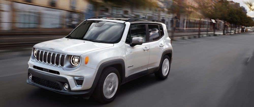 A white 2020 Jeep Renegade driving on a city street