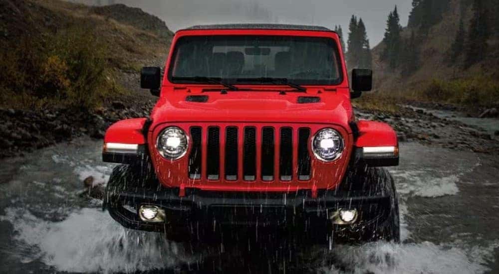 A red 2022 Jeep Wrangler Sport is shown driving through creek after leaving a Jeep dealer near Maysville.