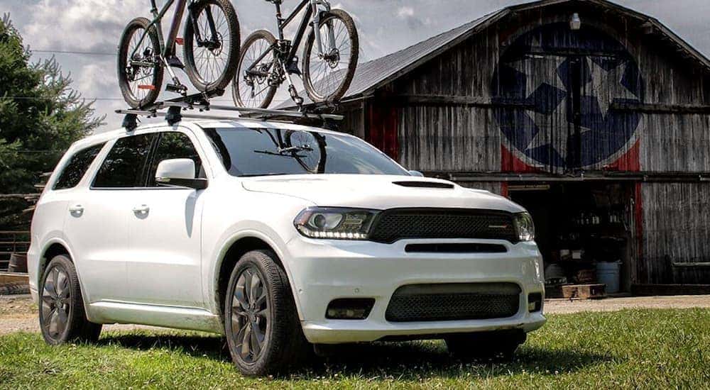 A white 2019 used Dodge Durango is parked outside of a barn.