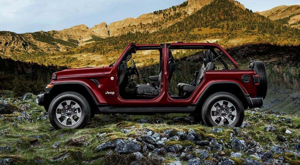 A burgundy 2021 Jeep Wrangler Sport Unlimited is shown from the side off-road.
