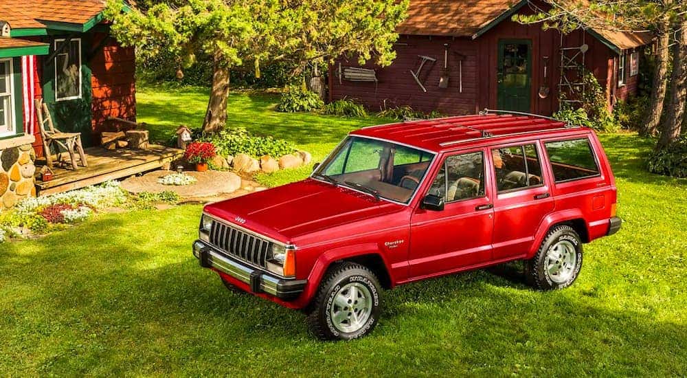 A red 1987 Jeep Cherokee is shown from a high angle parked in a grass yard after leaving a used Jeep dealer in Lexington.