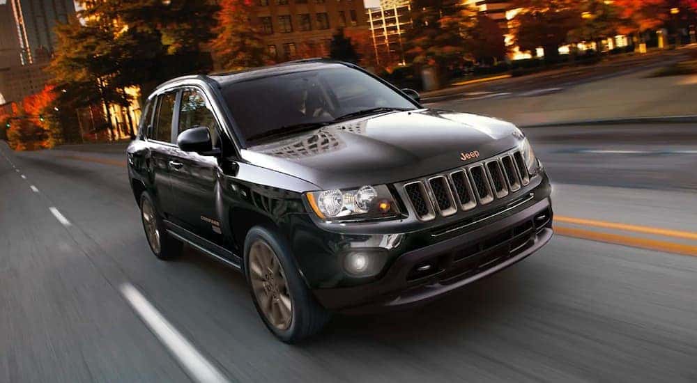 A black 2015 Jeep Compass is speeding down a blurred city street.