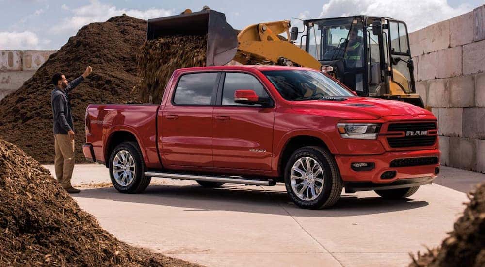 A red 2021 Ram 1500 is shown moving wood chips at a construction site.