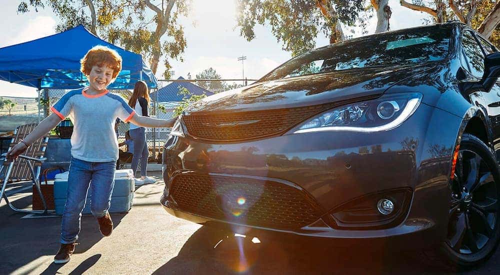 A child is running around a black 2021 Chrysler Pacifica.