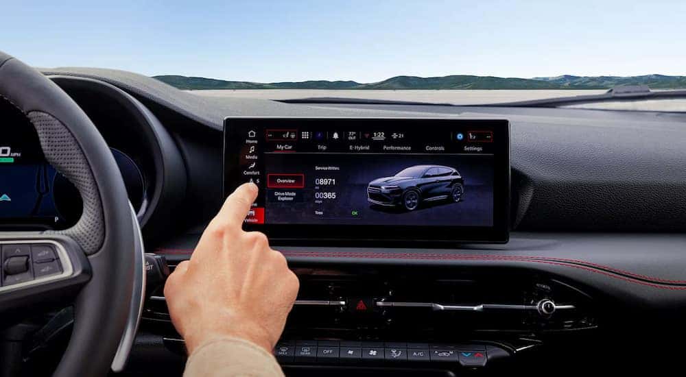 A person is shown using the infotainment screen in a 2024 Dodge Hornet at a Dodge dealership.