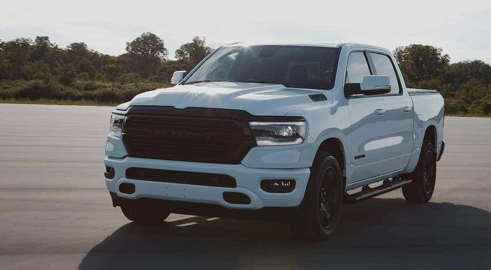A white 2020 used Ram Laramie 1500 Night Edition is shown driving on a sunny day.