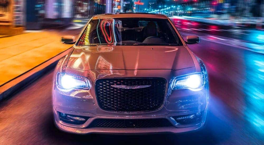 A white 2021 Chrysler 300 is shown from the front driving through the city after leaving a Lexington Chrysler dealership.