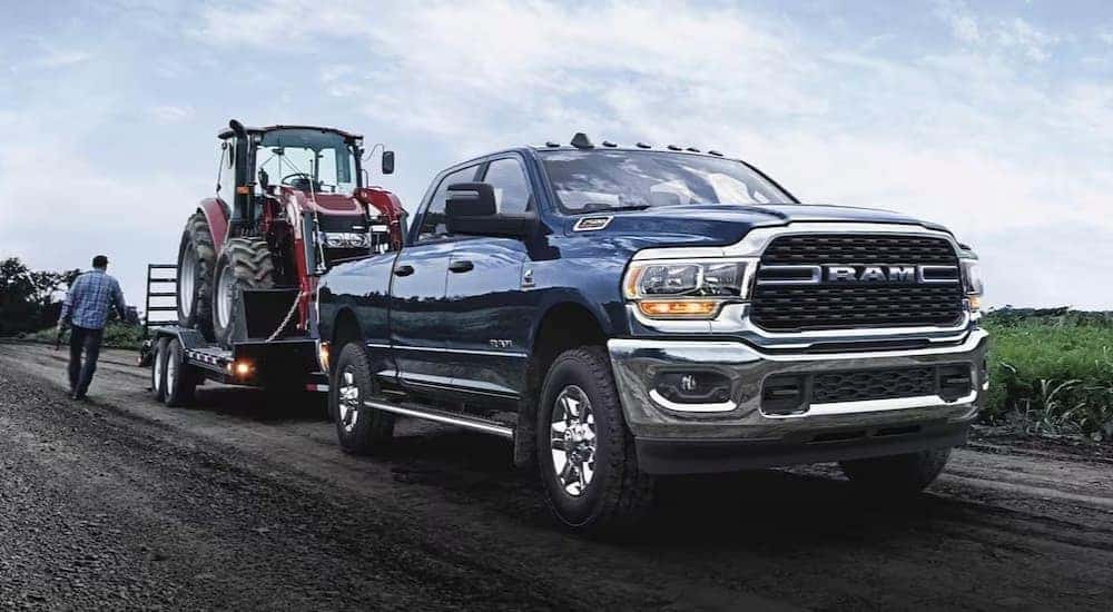 A blue 2024 Ram 2500 Laramie is shown towing a trailer to view a Ram 2500 for sale.