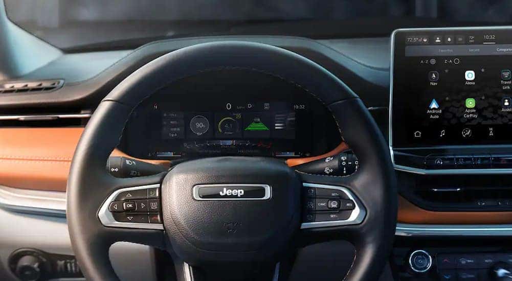 The black interior of a 2022 Jeep Compass shows the steering wheel in close up.
