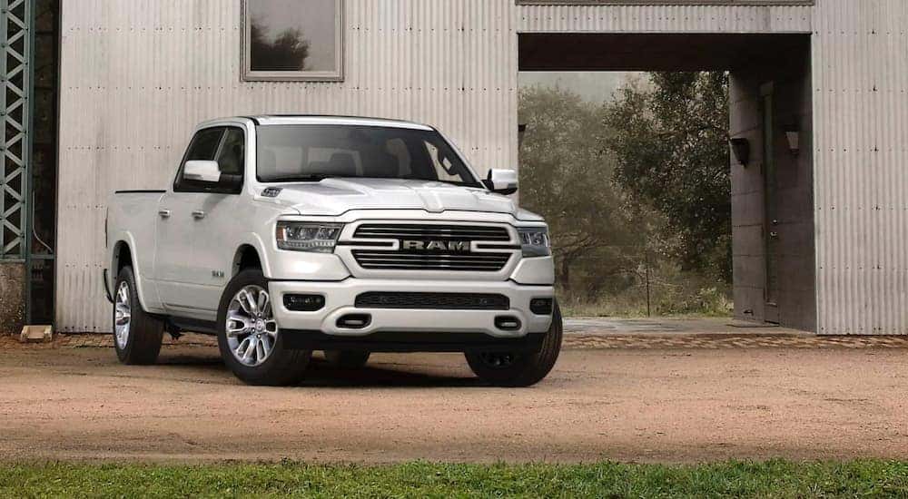 A white 2020 Ram 1500 is parked in front of a white barn.