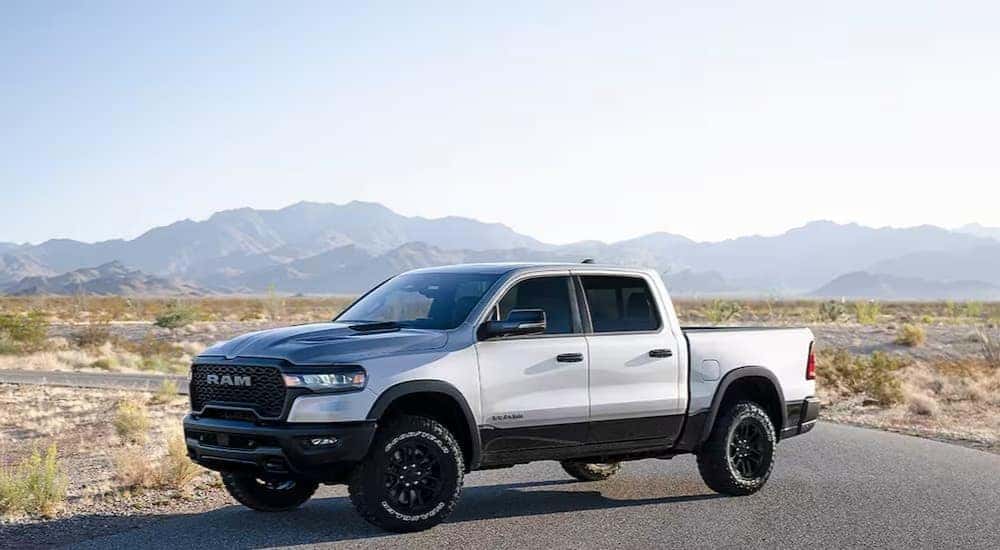 A white 2025 Ram 1500 for sale, is shown parked near mountains.