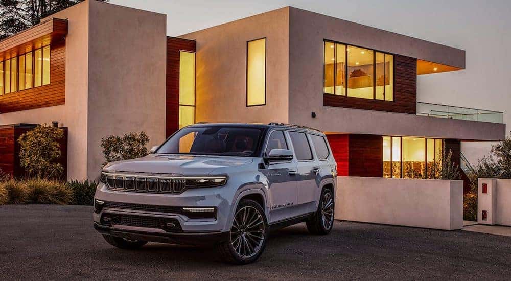 A grey 2021 Jeep Wagoneer is parked in front of a modern house.