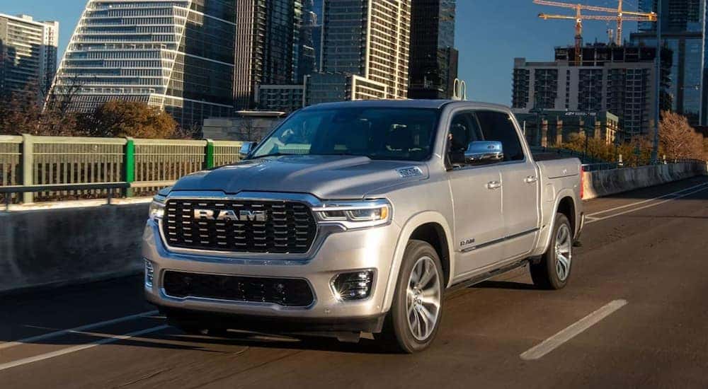 A silver 2025 Ram 1500 is driving on a city highway after leaving a Ram dealer near Somerset.