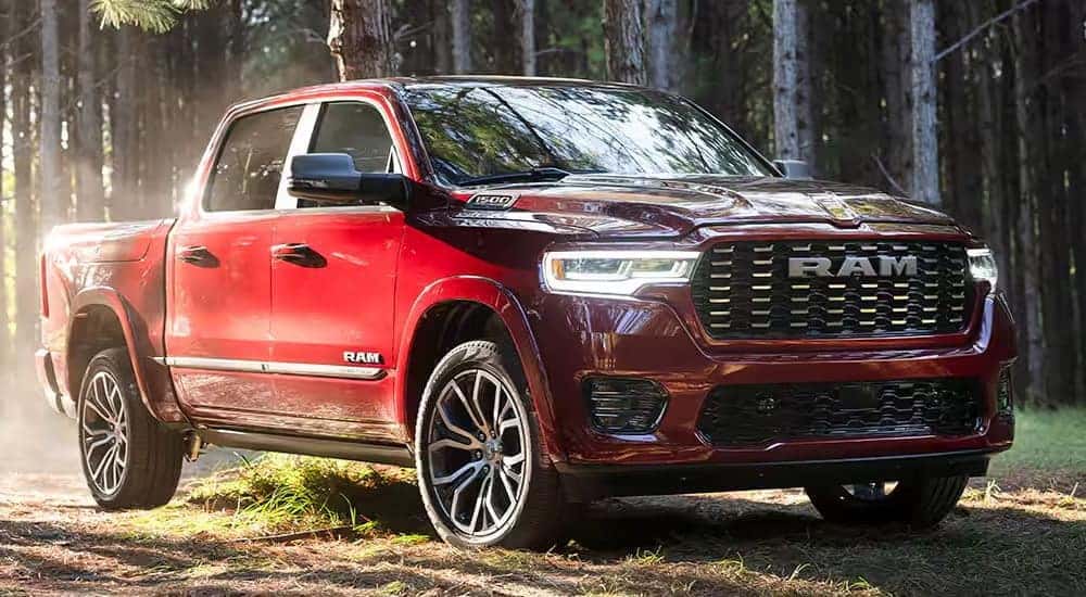 A red 2025 RAM 1500 parked off-road in a forest.