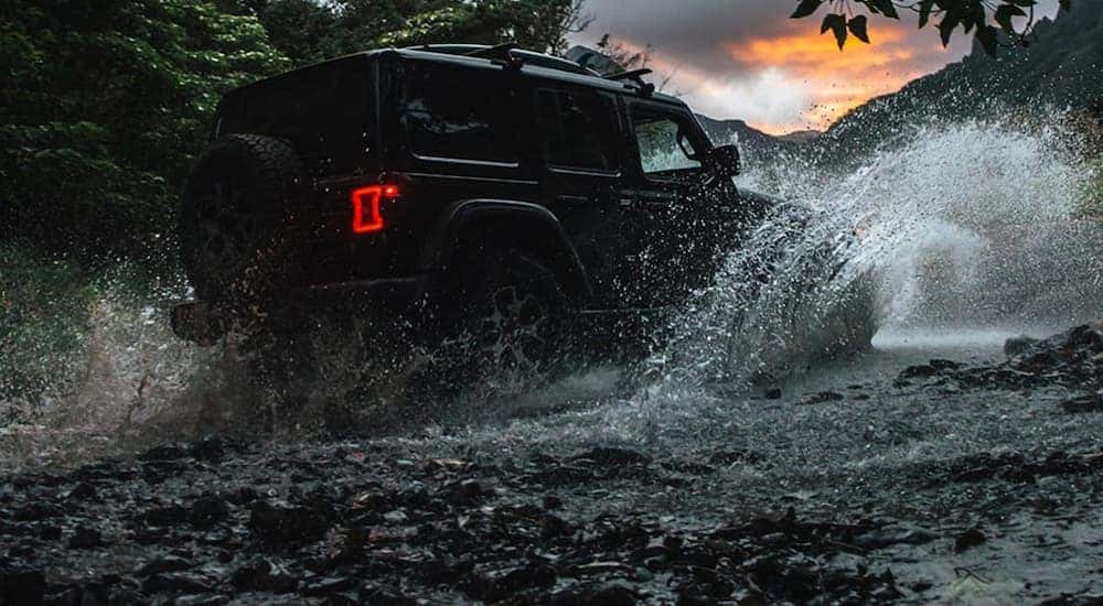 A black 2020 Jeep Wrangler Unlimited is crossing water while off-roading near Lexington, KY.