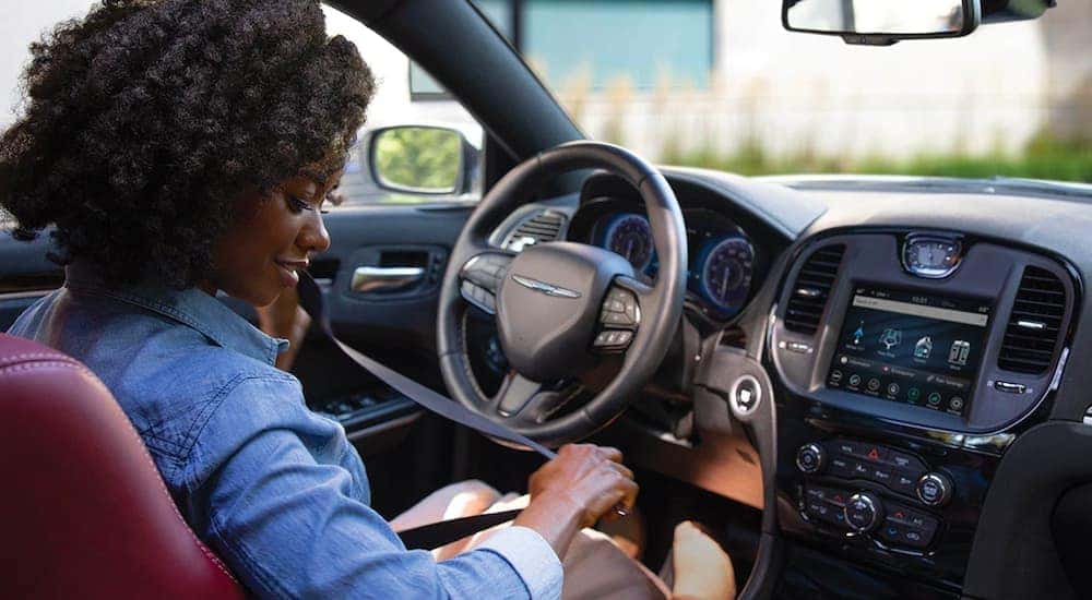 A woman is shown buckling her seatbelt in a 2021 Chrysler 300.