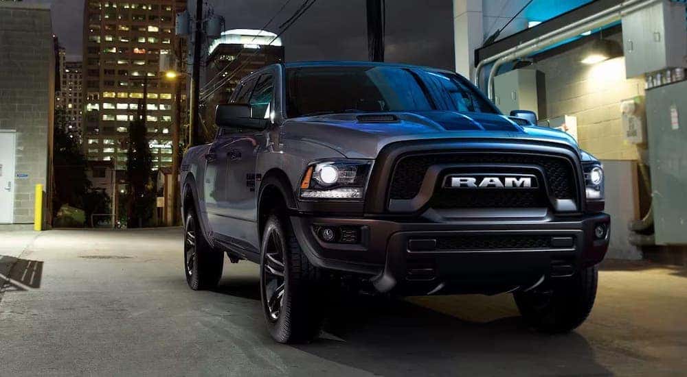 A black 2023 Ram 1500 is shown parked in a city by a used Jeep dealership near Lexington.