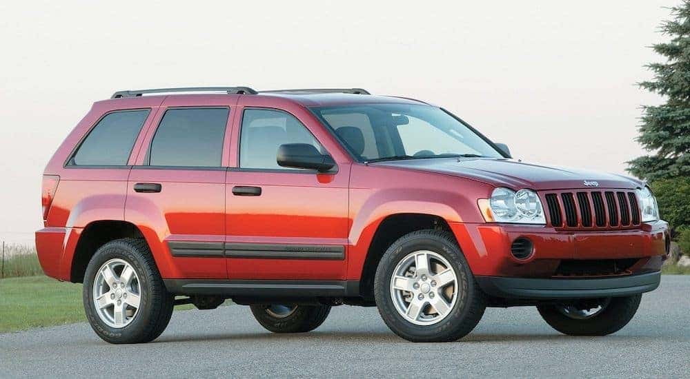 A red 2006 used Jeep Grand Cherokee is parked with blue sky in the background shown from a low angle.