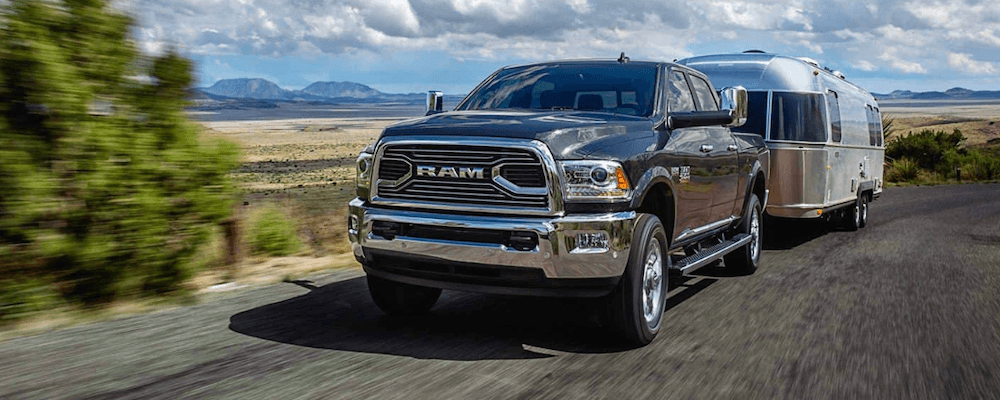 2018 RAM 2500 towing a trailer at full speed along an open road.