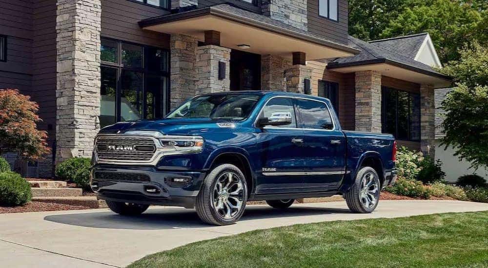 A blue 2023 Ram 1500 Big Horn is shown parked near a house.